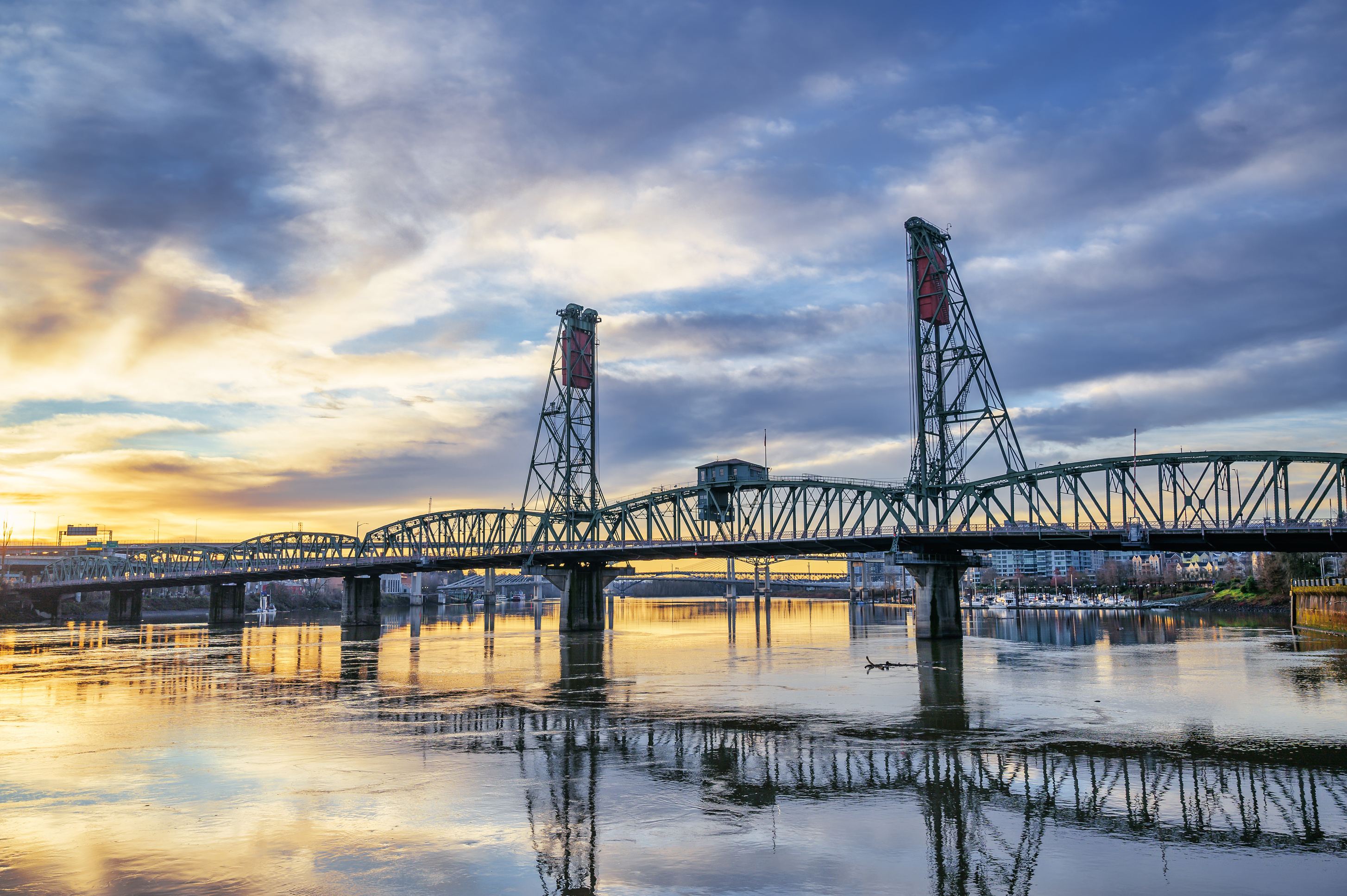 Truss bridge over river under sundown sky